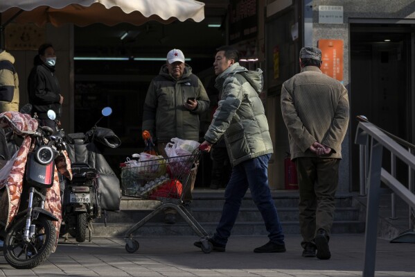 A man pushes over with ravens with shops from Beijing store on 26 March, 2025. (AP photo / andy wong)